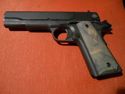 1994 Ford Bronco - A black pistol with camouflage grips rests on an orange textured surface.