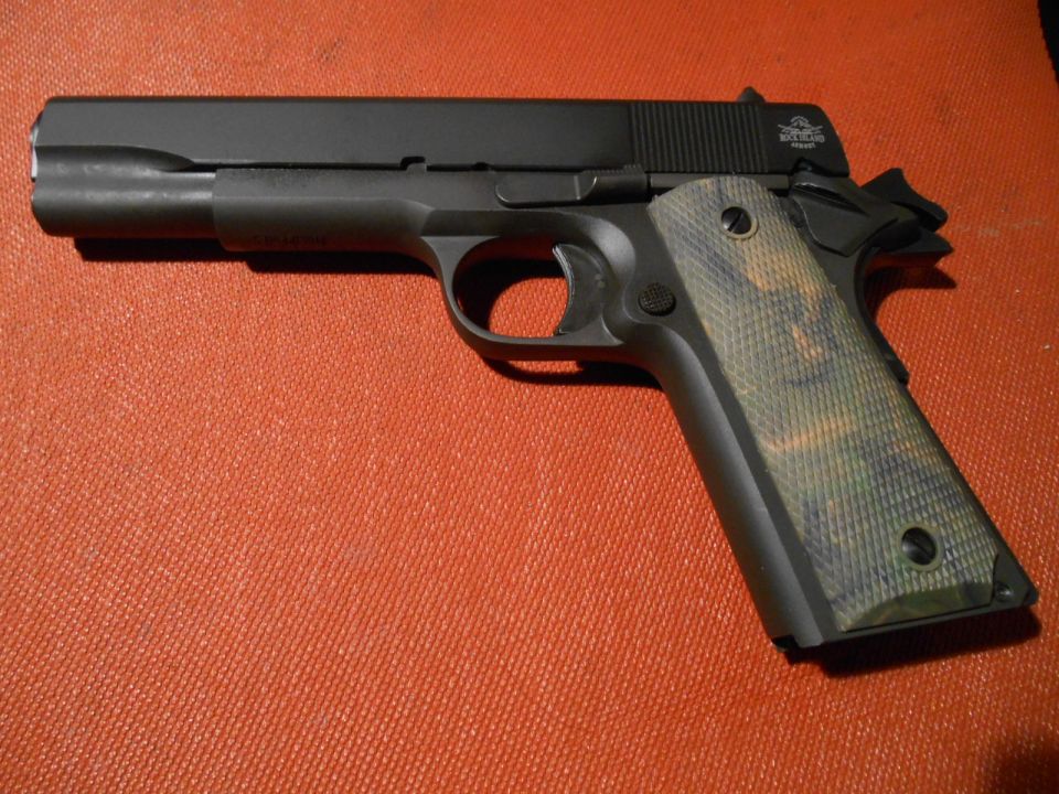 Black pistol with camouflage grips on an orange textured surface