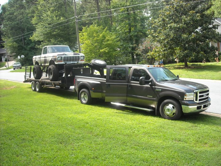 1979 Ford F-150 on trailer towed by modern Ford Super Duty pickup