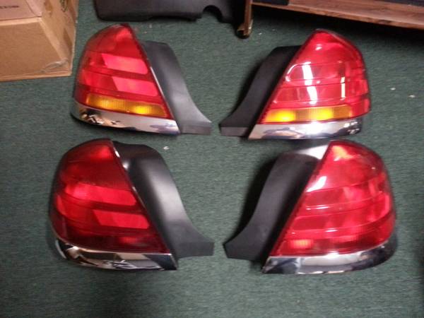 Four Crown Victoria tail light assemblies, two amber and two all-red, laid on green carpet