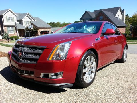 2008 Cadillac CTS - Red 2008 Cadillac CTS sedan with a sunshade on the windshield is parked in front of a suburban house.