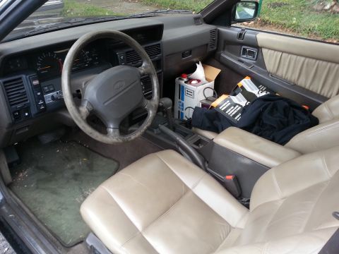 1991 Infiniti M30 - The interior of a 1991 Infiniti M30 shows tan leather seats and a center console with various items.