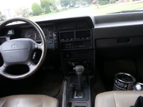 1991 Infiniti M30 - The interior of a 1991 Infiniti M30 features a tan leather interior, a four-spoke steering wheel with the Infiniti logo, and a dark gray da…