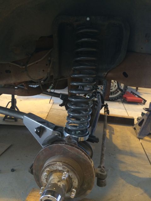 1996 Ford Bronco - Installing a new coil spring on a vehicle's suspension system, with a Supermotors logo in the corner.