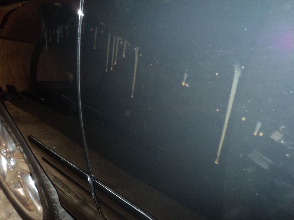 Dark car door with streaks of dirt and grime, chrome wheel visible
