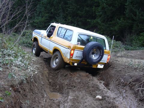 1991 Ford Bronco - This two-tone Ford Bronco navigates a challenging muddy terrain, its off-road capabilities.