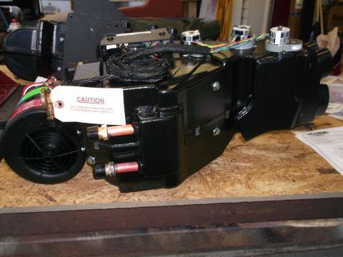 1967 Ford Mustang - A black automotive HVAC unit sits on a wooden surface, a caution tag and visible wiring.