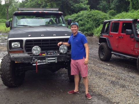 1979 Ford Bronco - A man stands beside a modified black Ford truck, with a red Jeep visible to the right.