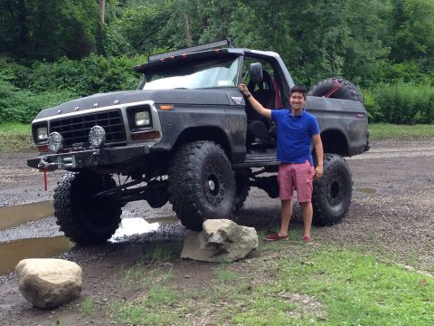 1979 Ford Bronco - A lifted 1979 Ford Bronco with a man posing next to the open driver's door, ready for off-road adventure.
