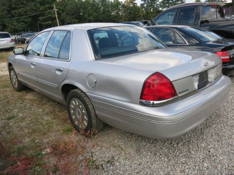 1991 Ford LTD Crown Victoria - A silver Ford Crown Victoria is parked on a gravel lot with other vehicles in the background.