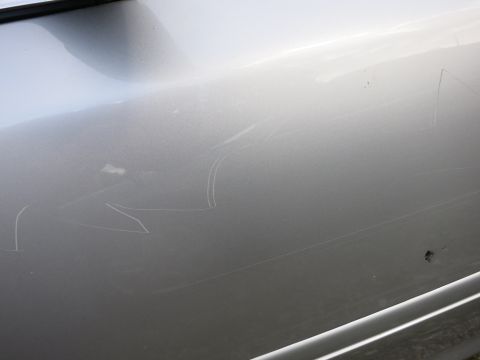 1991 Ford LTD Crown Victoria - Close-up of a silver car door showing extensive damage from scratches.