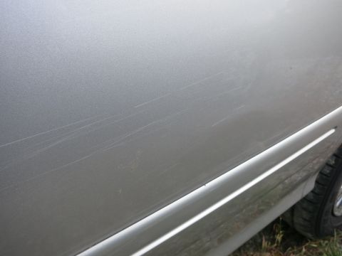 1991 Ford LTD Crown Victoria - Close-up of a silver car door showing extensive scratches along its length.