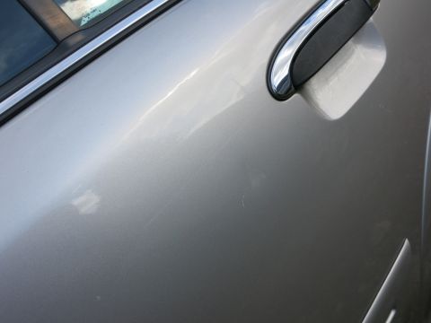 1991 Ford LTD Crown Victoria - The side of a silver vehicle is shown, with reflections on the paint and chrome trim around the window.