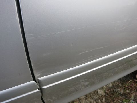 1991 Ford LTD Crown Victoria - Close-up view of a silver car's side panel showing extensive scratches and a prominent body line.