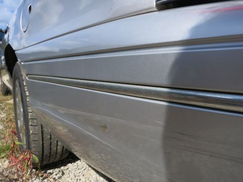 1991 Ford LTD Crown Victoria - The side of a silver sedan is shown, with a chrome trim piece running along the lower body panel.