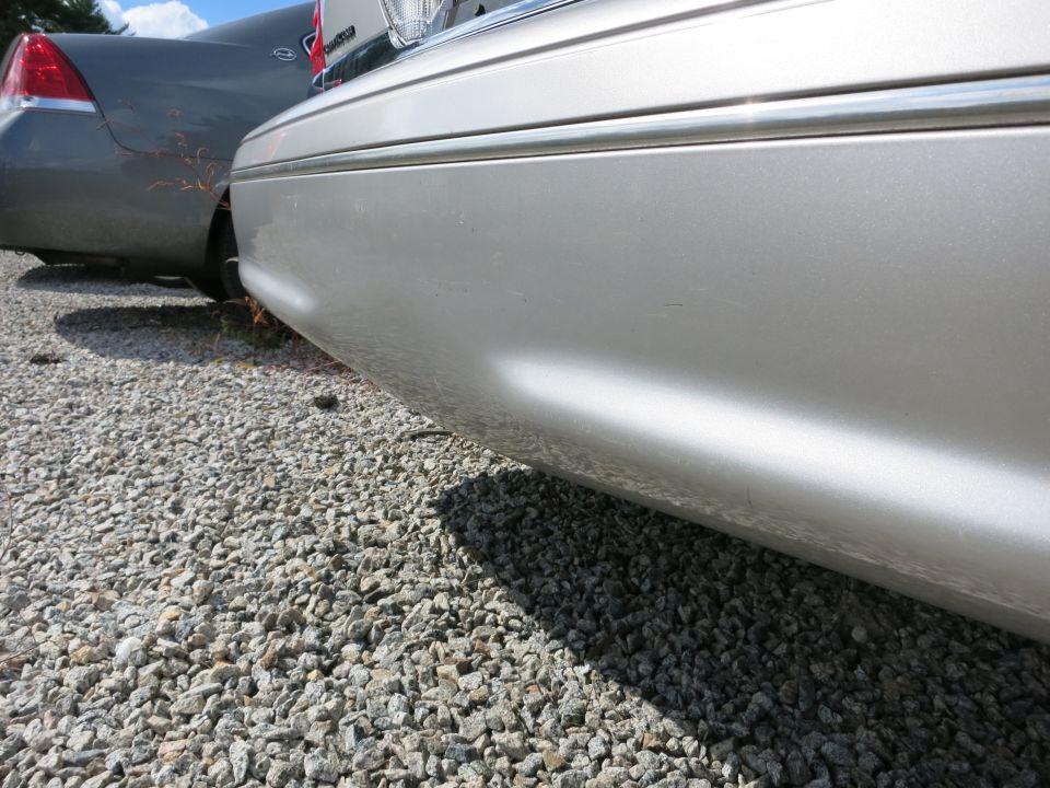Silver car's rear quarter panel and bumper, parked next to a gray car