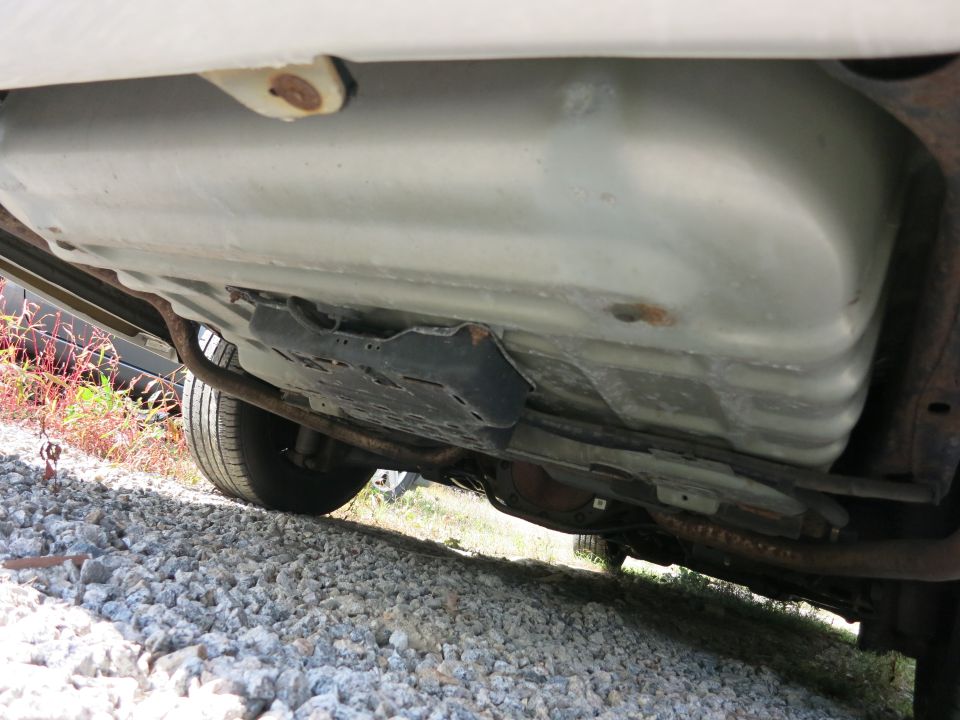 Underside view of a vehicle showing the fuel tank and exhaust system