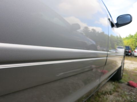 1991 Ford LTD Crown Victoria - Side view of a silver car's body panel and trim, with other vehicles in the background.