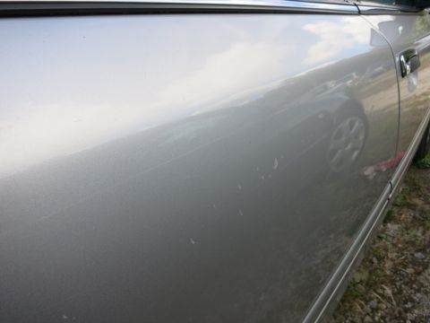 1991 Ford LTD Crown Victoria - Close-up of a silver car's side door showing minor damage and reflections.