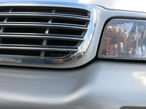 1991 Ford LTD Crown Victoria - The front grille and headlight assembly of a silver Ford Crown Victoria are shown in this close-up photograph.