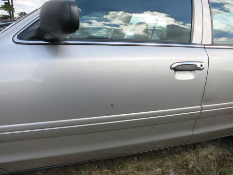 1991 Ford LTD Crown Victoria - Side view of a silver sedan's door, showing minor imperfections and a chrome door handle.