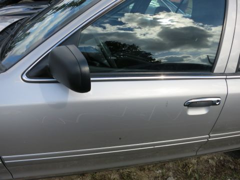 1991 Ford LTD Crown Victoria - Side view of a silver sedan, showing its door, side mirror, and chrome door handle. Scratches are visible on the paintwork.