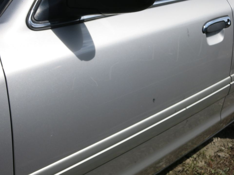 Silver car door with visible scratches and a chrome door handle
