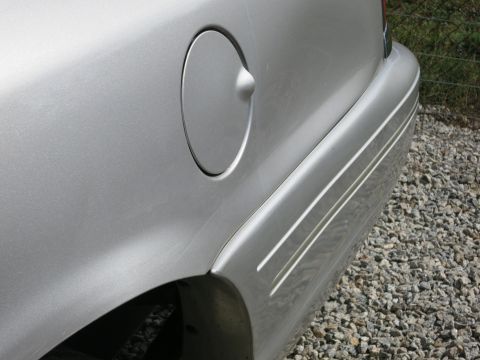1991 Ford LTD Crown Victoria - A close-up view of the rear side of a silver car, highlighting the fuel filler door and a decorative pinstripe.