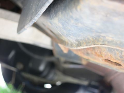 1991 Ford LTD Crown Victoria - Close-up view of the rusty undercarriage of a vehicle, revealing structural components and suspension elements.