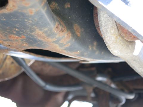 1991 Ford LTD Crown Victoria - The undercarriage of the vehicle shows significant rust and corrosion on its components.