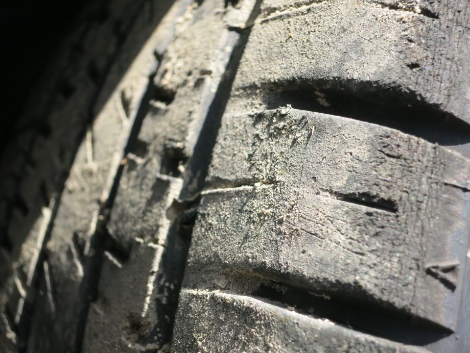 Close-up of a worn tire tread covered in dust and dirt