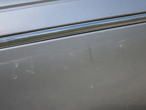 1991 Ford LTD Crown Victoria - Close-up of a silver car door showing chrome trim and numerous scratches.
