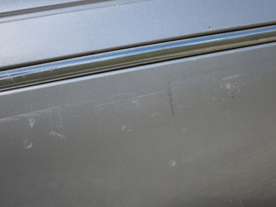 Silver car door with chrome trim and scratches