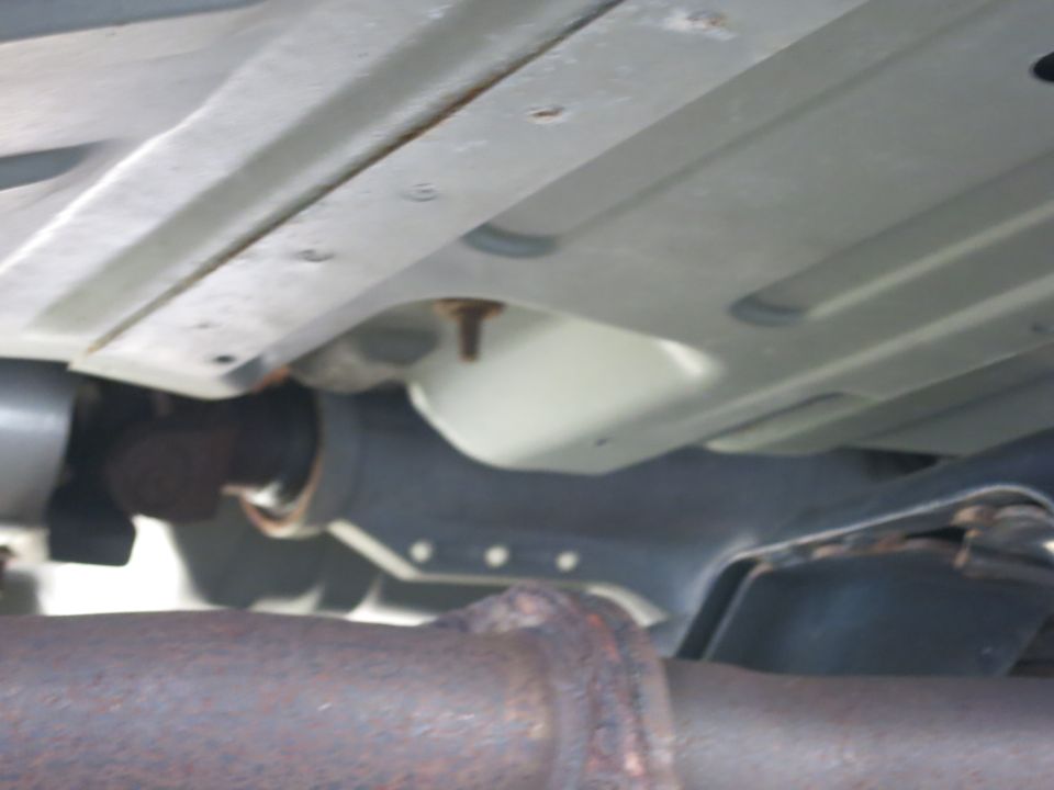 Underside view of a vehicle showing the exhaust pipe and frame components