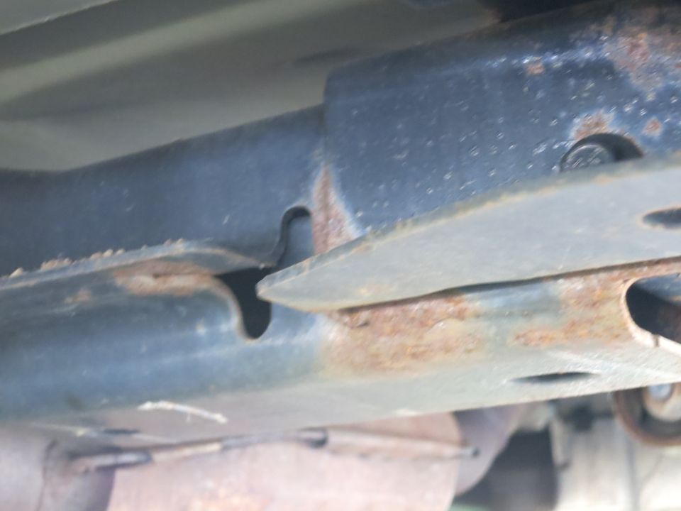 Close-up of rusted metal frame components with visible bolts and cutouts
