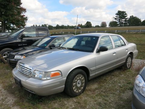 1991 Ford LTD Crown Victoria - A silver Ford Crown Victoria is parked in a lot with other vehicles under a cloudy sky.