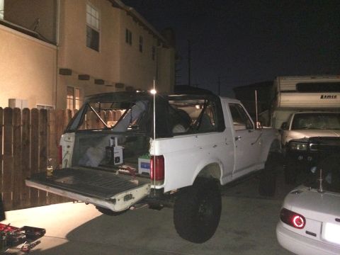 1990 Ford Bronco - This 1990 Ford Bronco is seen with its soft top removed and tailgate open, parked in a residential driveway at night.