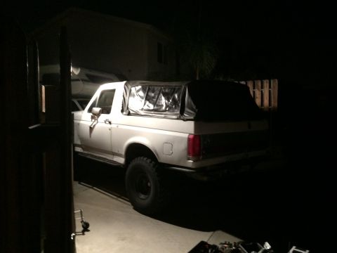 1990 Ford Bronco - The rear quarter panel and taillight of a white SUV with a soft top are visible.