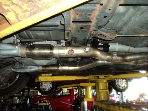 2004 Mercury Grand Marquis - The underbody exhaust system of a 2004 Mercury Grand Marquis is visible while the vehicle is raised on a service lift.