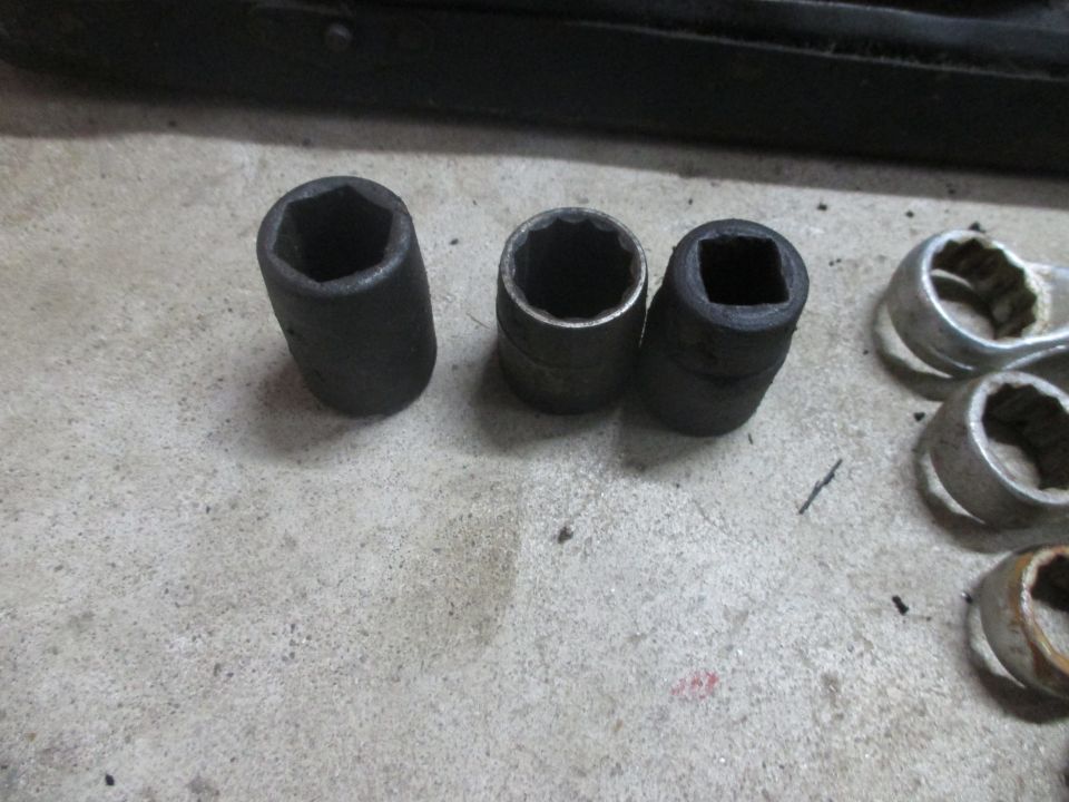 Three socket wrenches and other metal tools on a concrete surface
