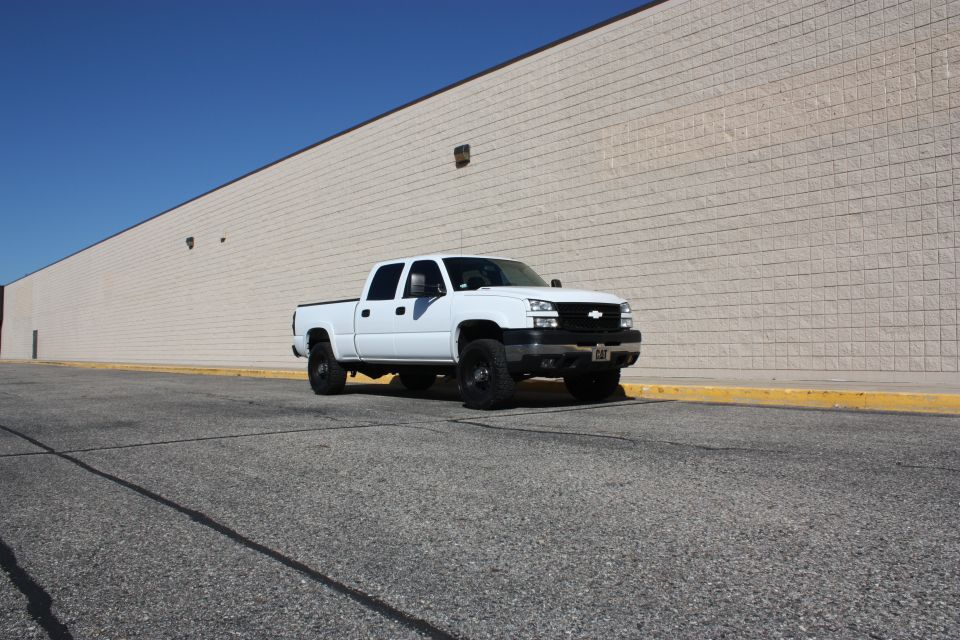 White 2006 Chevrolet Silverado 2500 parked in front of a beige brick wall