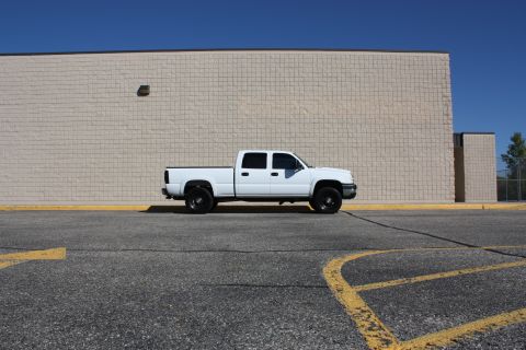 2006 Chevrolet Silverado 2500 - White 2006 Chevrolet Silverado 2500 pickup truck parked in a lot with a brick building behind it.