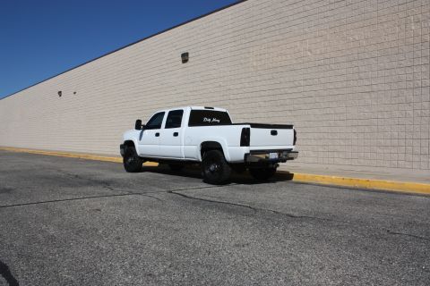 2006 Chevrolet Silverado 2500 - This white 2006 Chevrolet Silverado 2500 pickup truck is seen from the rear 3/4 angle parked next to a brick wall.