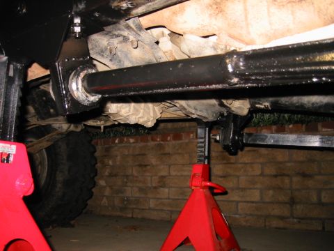 1985 Ford Bronco - The underside of a 1985 Ford Bronco is visible, supported by red jack stands.