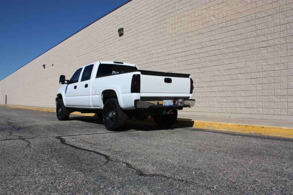 White pickup truck with tinted taillights and aftermarket wheels parked on asphalt