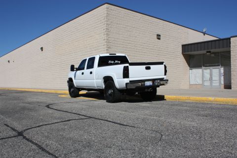 2006 Chevrolet Silverado 2500 - Rear view of a white 2006 Chevrolet Silverado 2500 pickup truck parked in front of a brick building.