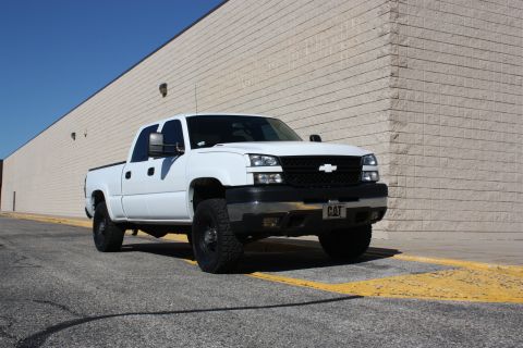 2006 Chevrolet Silverado 2500 - A white pickup truck is parked in front of a building with a CAT license plate.