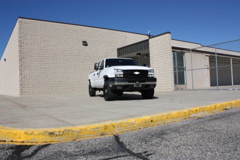 2006 Chevrolet Silverado 2500 - A white 2006 Chevrolet Silverado 2500 pickup truck is parked on a concrete lot in front of a building.