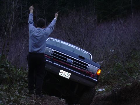 1991 Ford Bronco - A person celebrates next to a blue 1991 Ford Bronco 4x4 on an off-road trail.