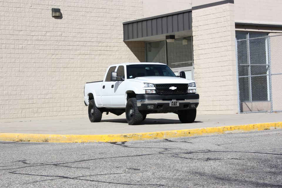 White 2006 Chevrolet Silverado 2500 pickup truck parked in front of a building